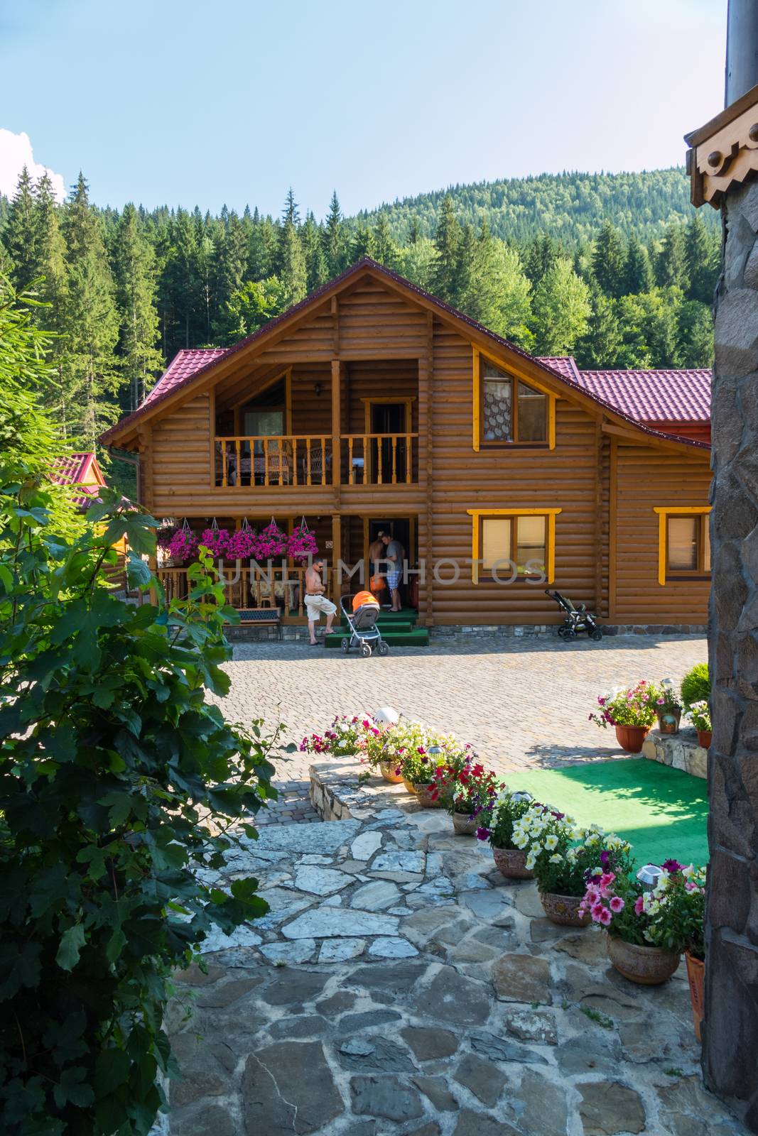 a wooden house with a clean, beautiful courtyard on the background of green wooded mountains