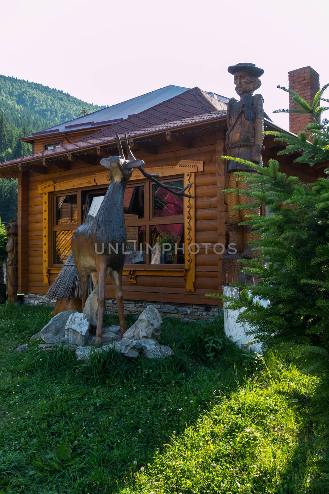 wooden reindeer on stones near the Hutsul house in the mountains by Adamchuk