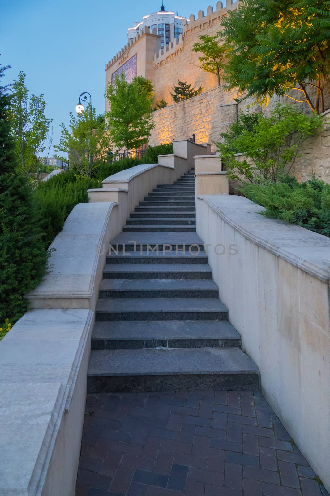 Narrow staircase with handrails going upwards to a high wall with an ornament with a jagged top. by Adamchuk