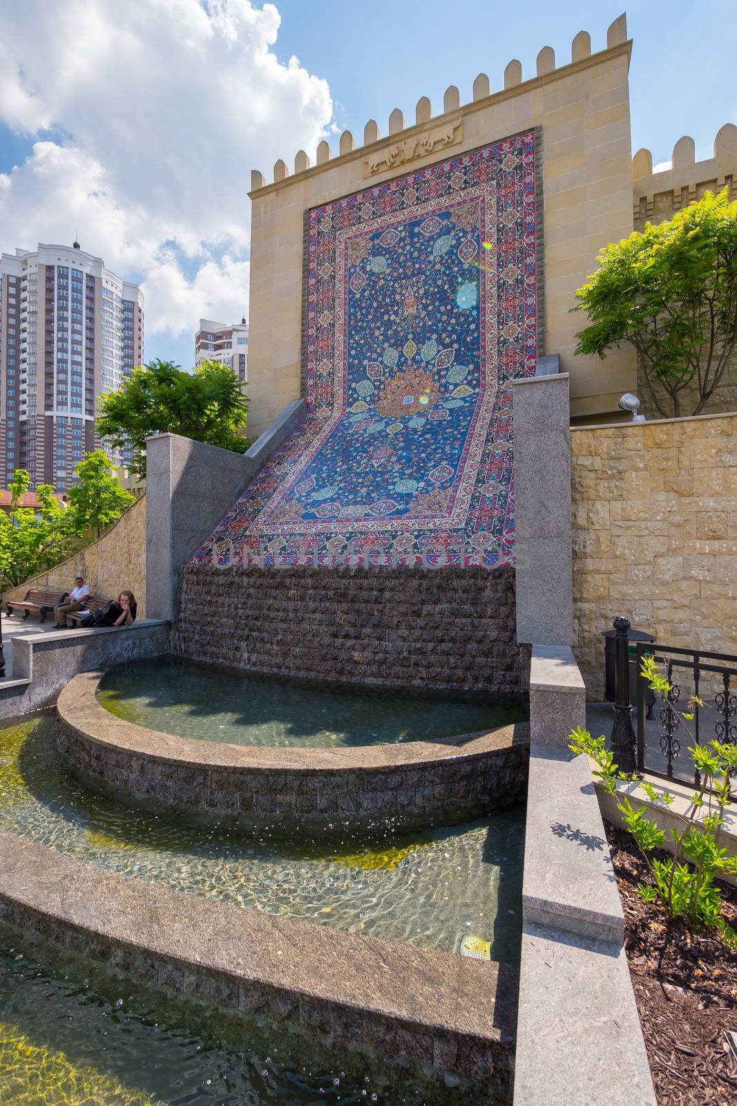 A small decorative cascading fountain near the wall, which depicts an Azerbaijani carpet by Adamchuk