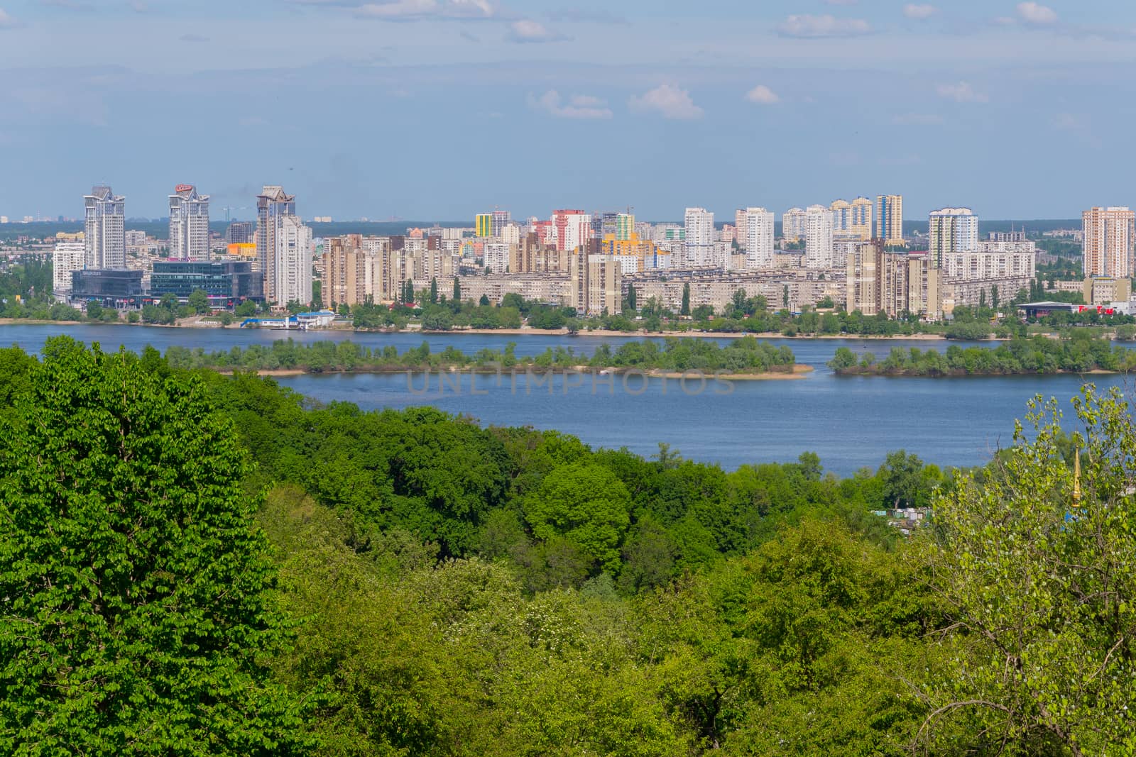 Panorama of multi-storey buildings on the shore of the Dnipro River under the blue sky. Kiev. Ukraine