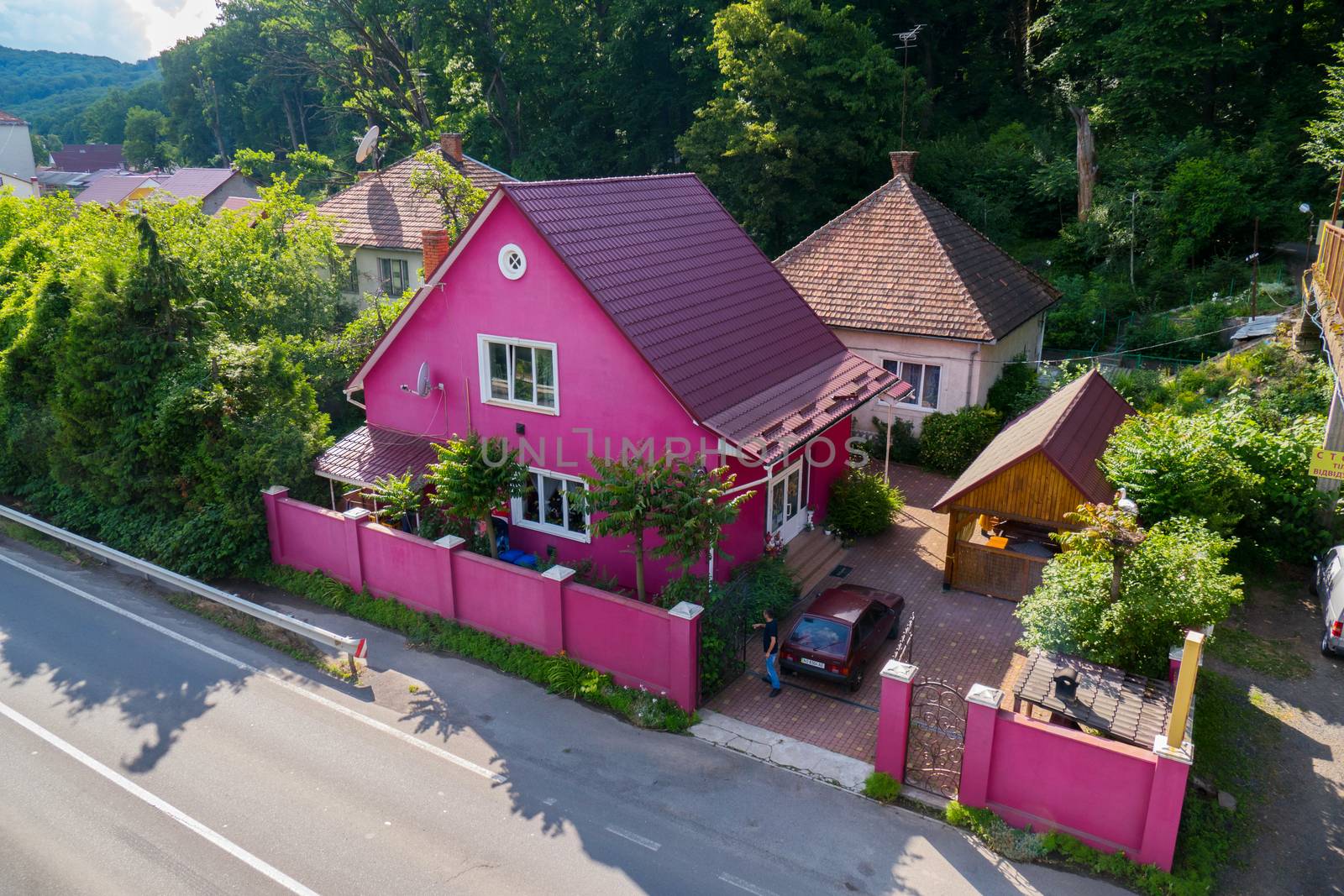 A nice pink house with a high fence and a wooden gazebo in the yard