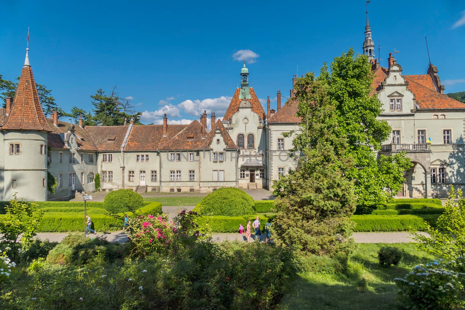 An ancient estate with two wings with beautiful balconies with a park in the courtyard with a green designer lawn, bushes of tsvetov and trees.