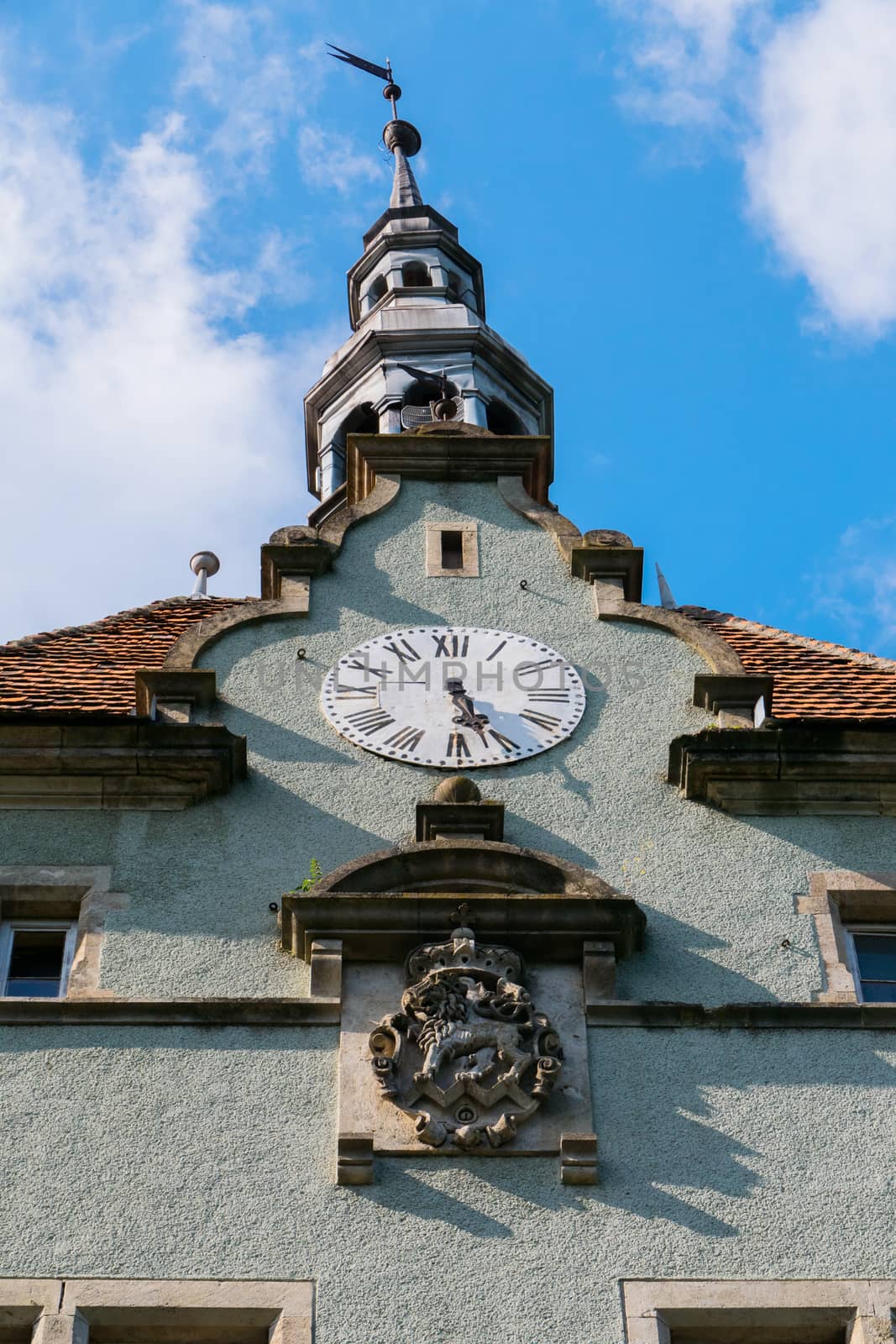 An ancient chapel with a red roof made of shingles against a blue sky