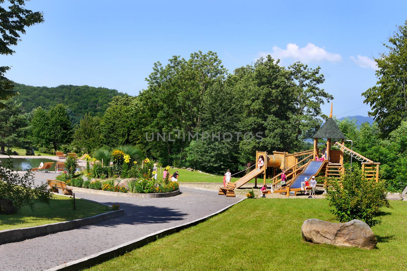 The park walking alley leading to a decorative round flower bed and a large playground