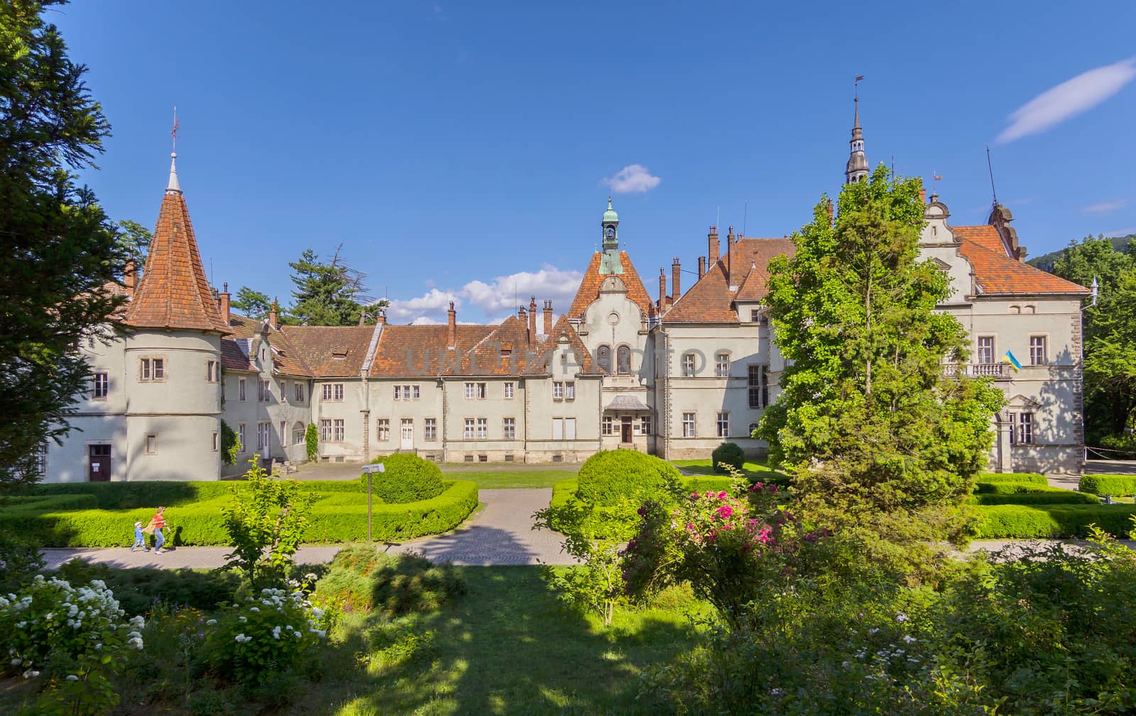 Authentic ancient Ukrainian castle with a red roof against the background of green trees and bushes