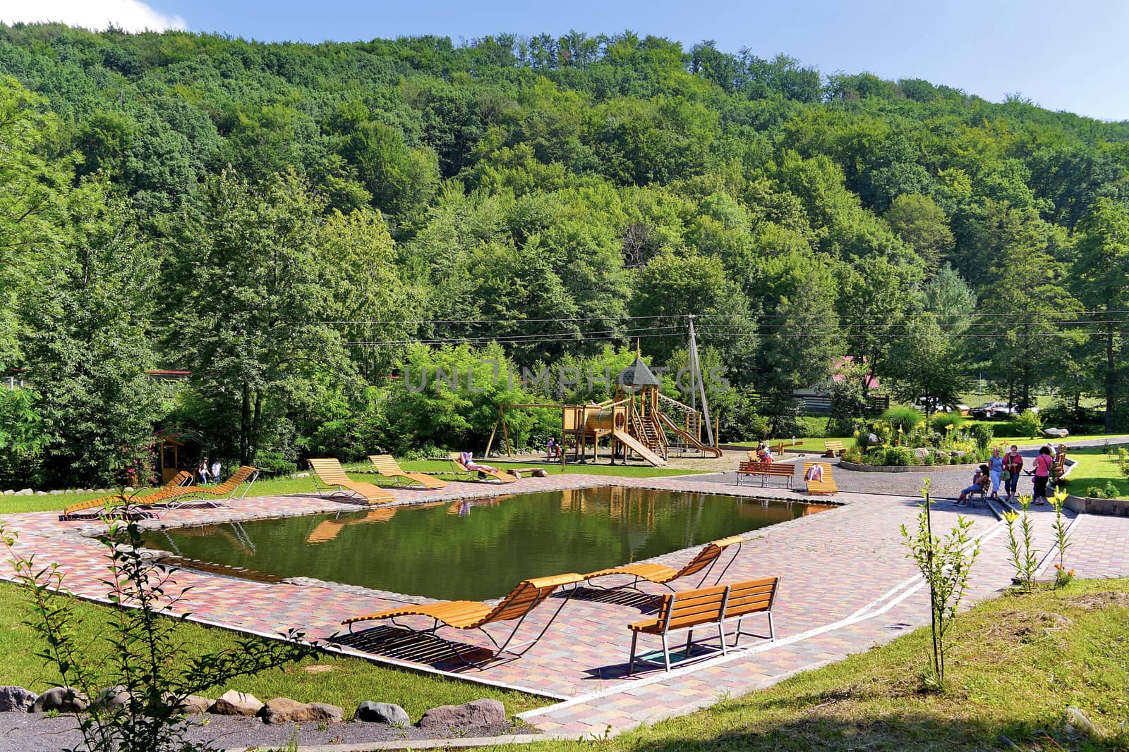 a large pool with wooden lounges on the base of rest in the mountains