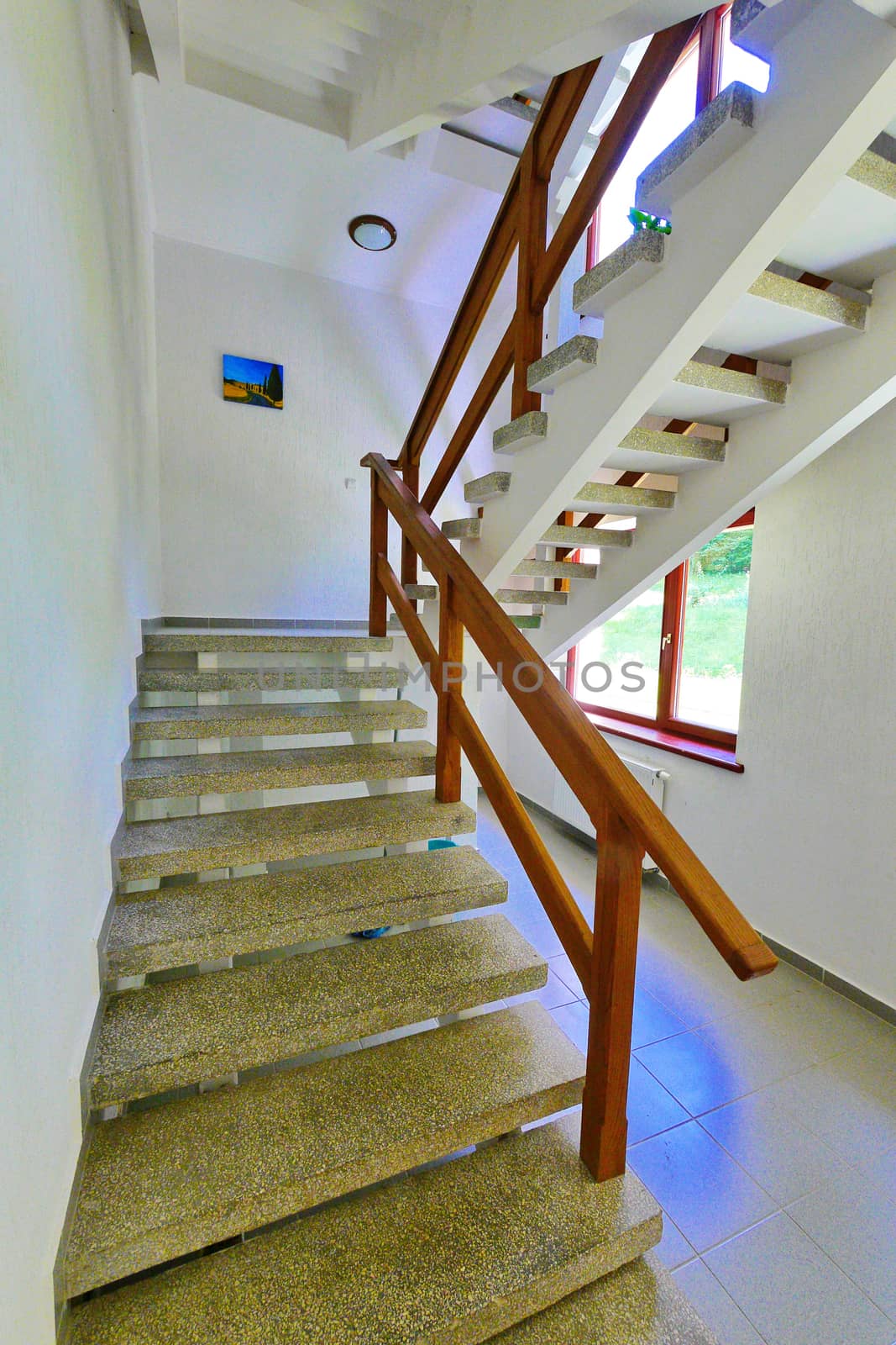 stone staircase with wooden railings and a picture between the floors