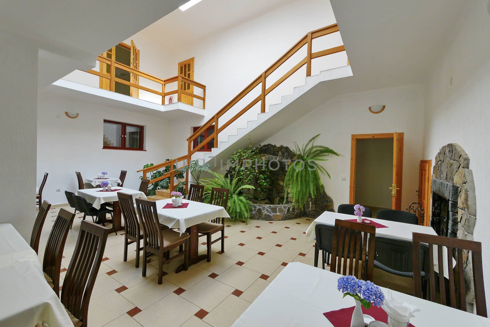 A beautiful two-story cafe. The design is executed in a white-brown style, with natural wooden handrails