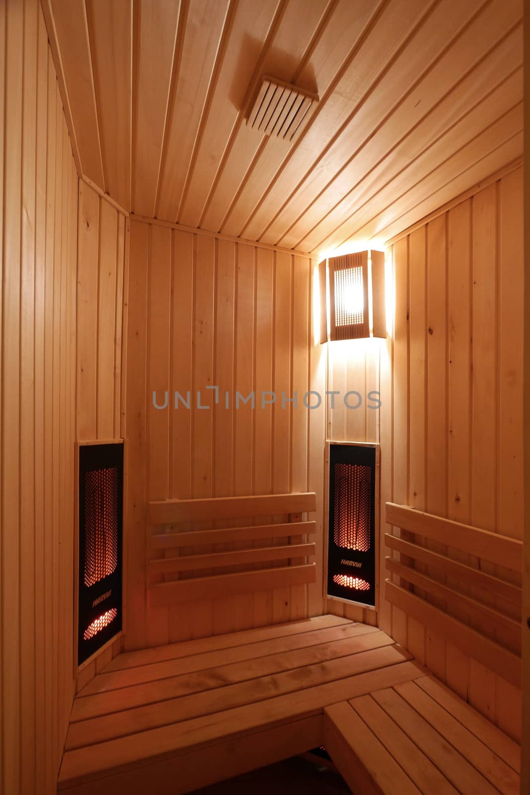 a room in a sauna lined with wood with a soft light of a wall lamp by Adamchuk