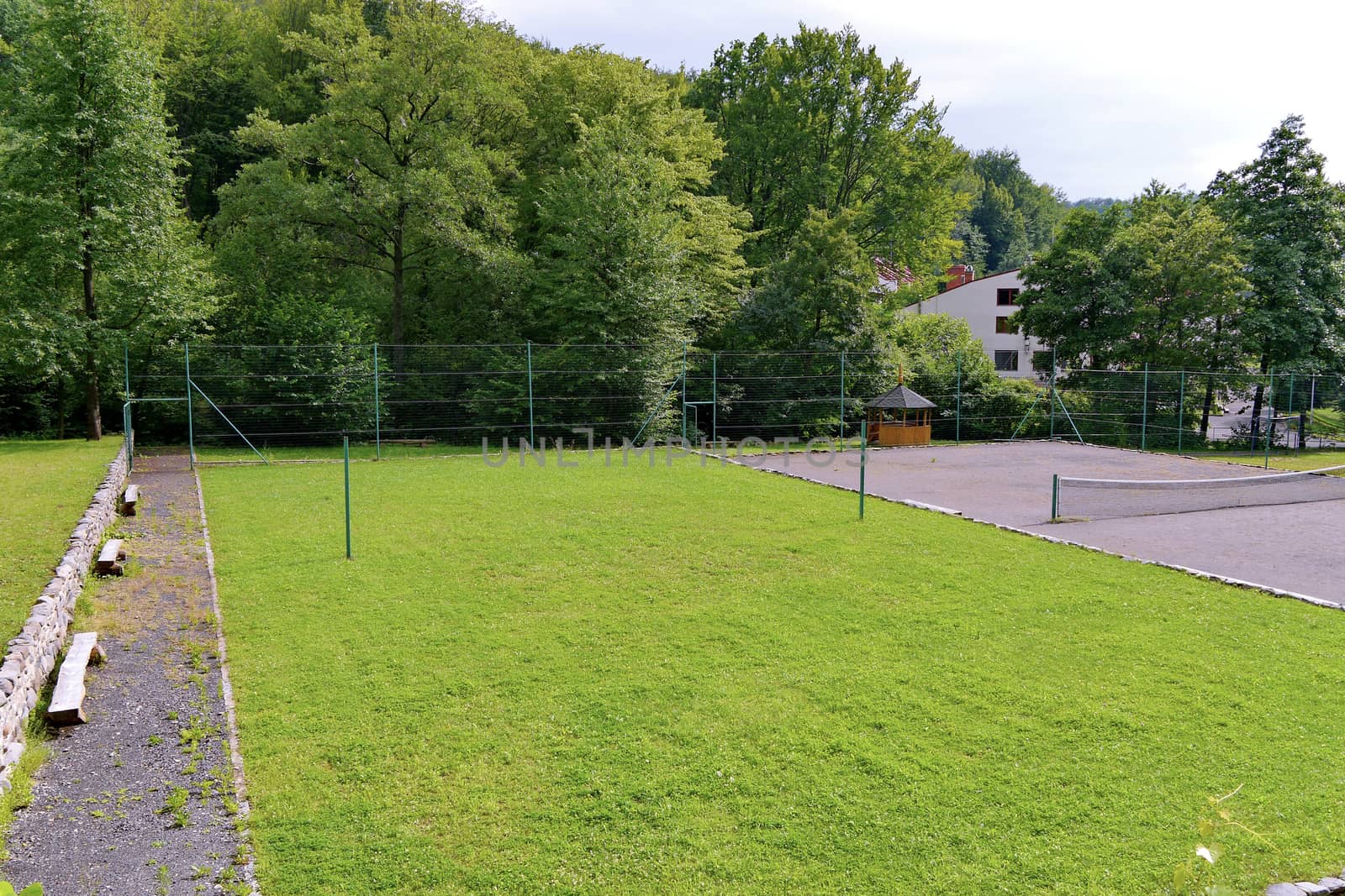 Tennis court with two courts: one with a grass cover, and the second with asphalt