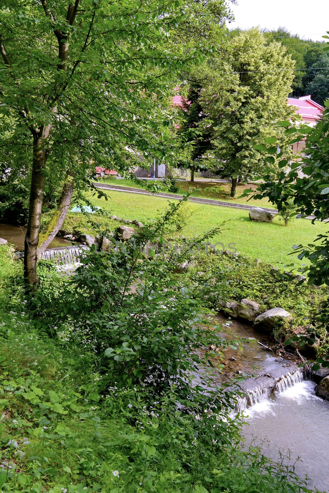 The thresholds of a small river against the backdrop of a beautiful park area at the hotel complex