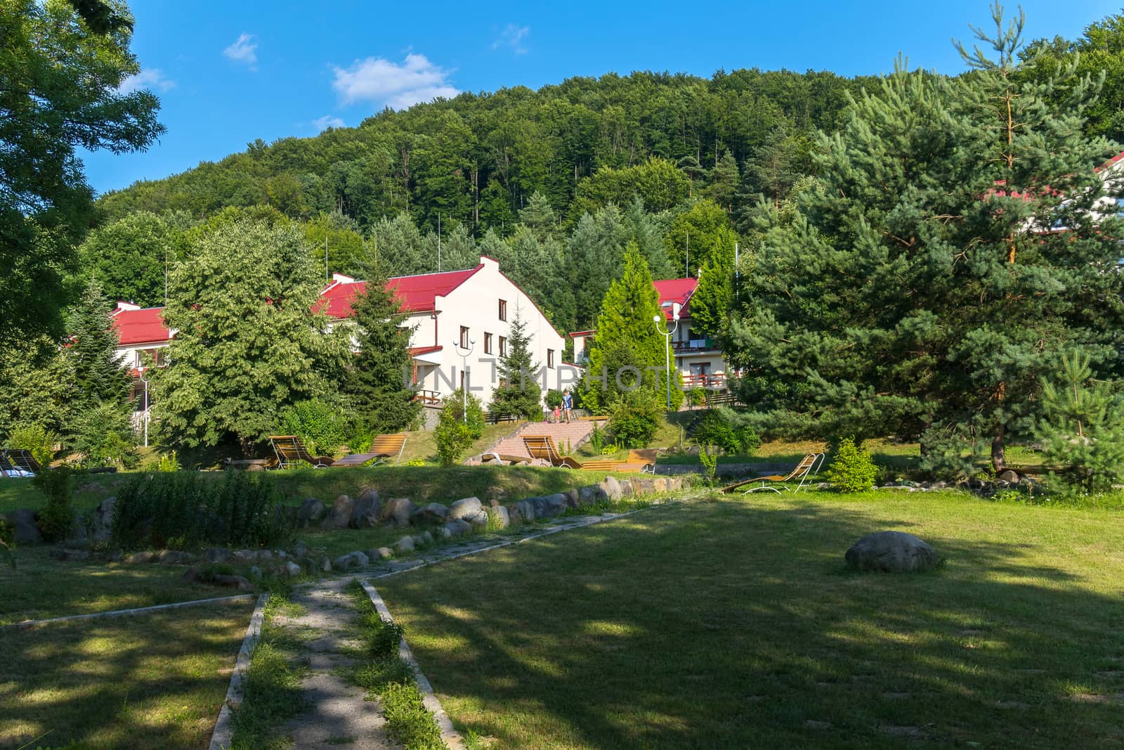 The hotel complex is on a small hill in the middle of a beautiful nature with stairs leading to a hillock and sun beds below it.