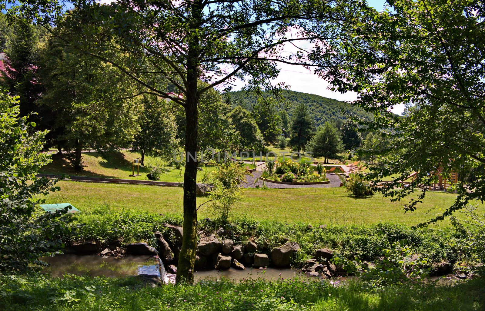 Decorative stone river rapids on the background of the beautiful green park zone of the hotel complex
