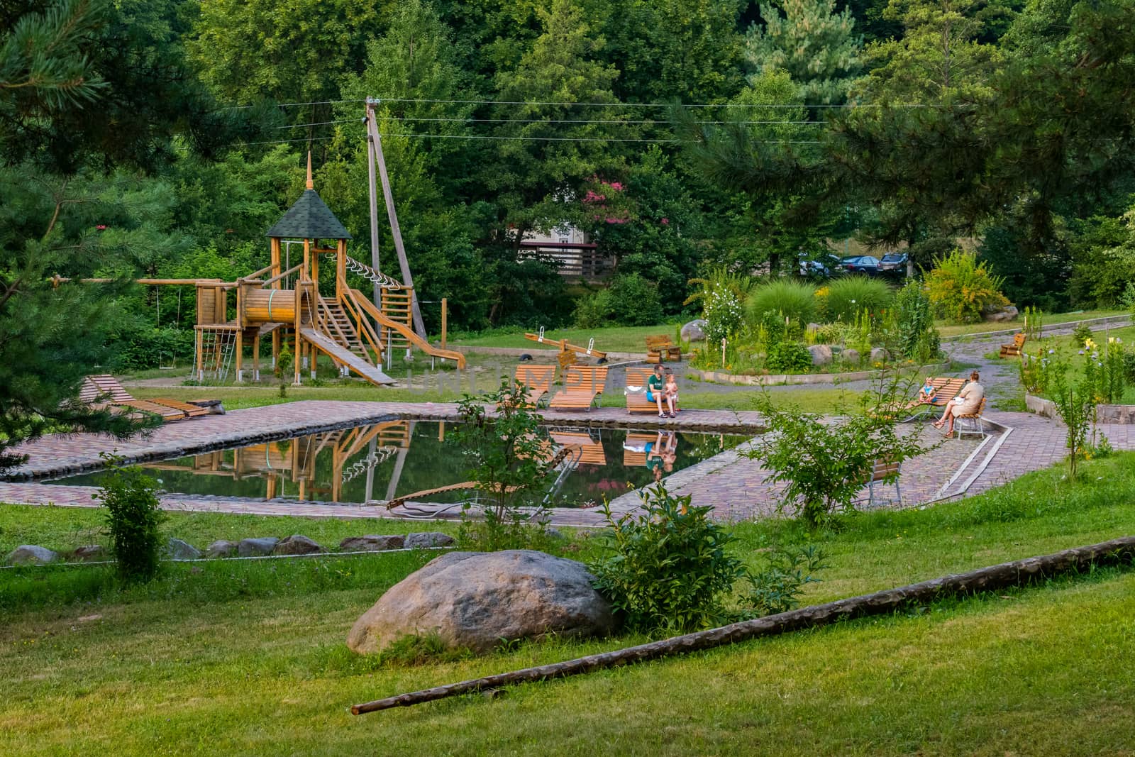 Father with a child on a bench in a park with a play area of wooden beams