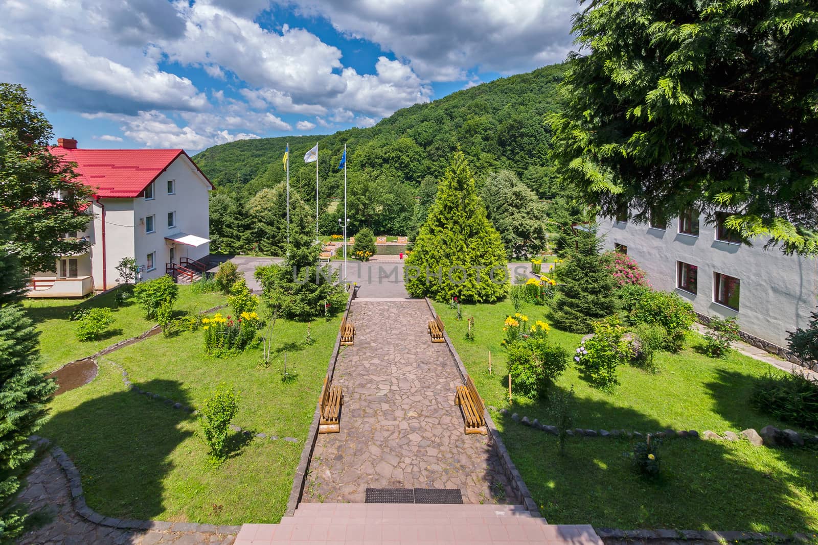 Alley going through the park and separating the two houses from each other. On the sides are benches