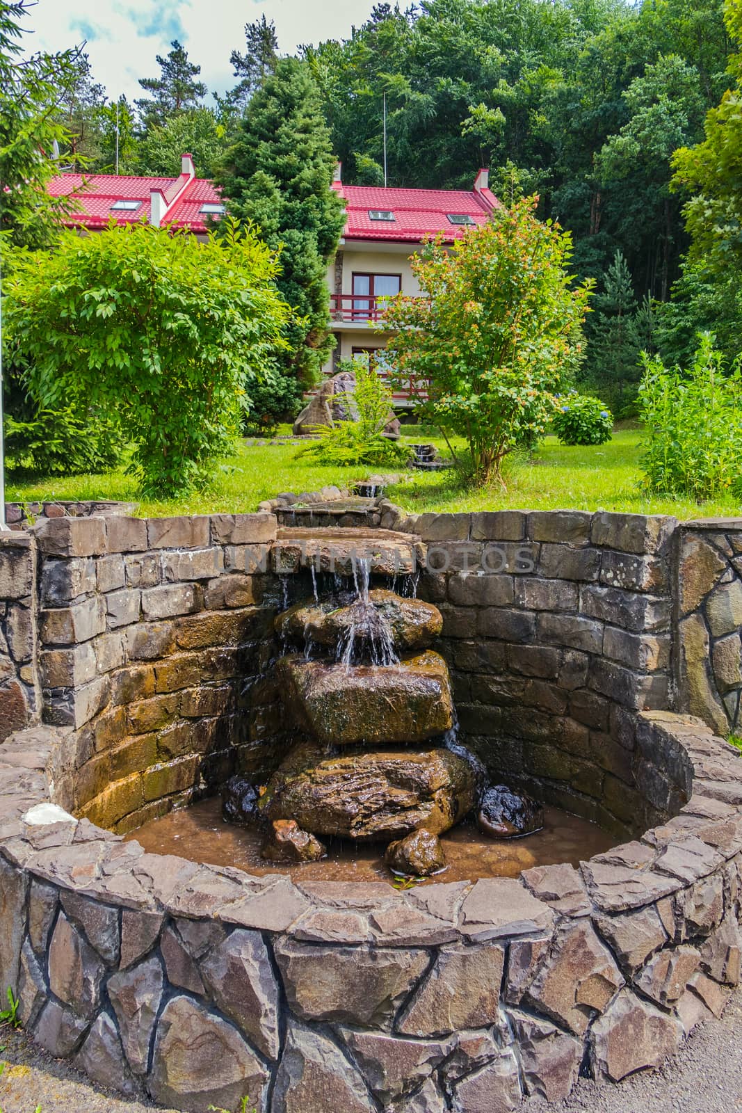 A miniature waterfall in the form of a stream of water running downwards over the stones laid out by hand. by Adamchuk