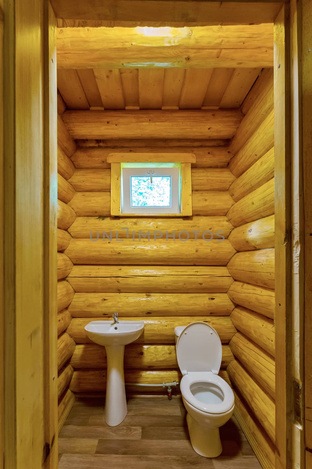 white toilet with washbasin in a wood-lighted sauna room by Adamchuk