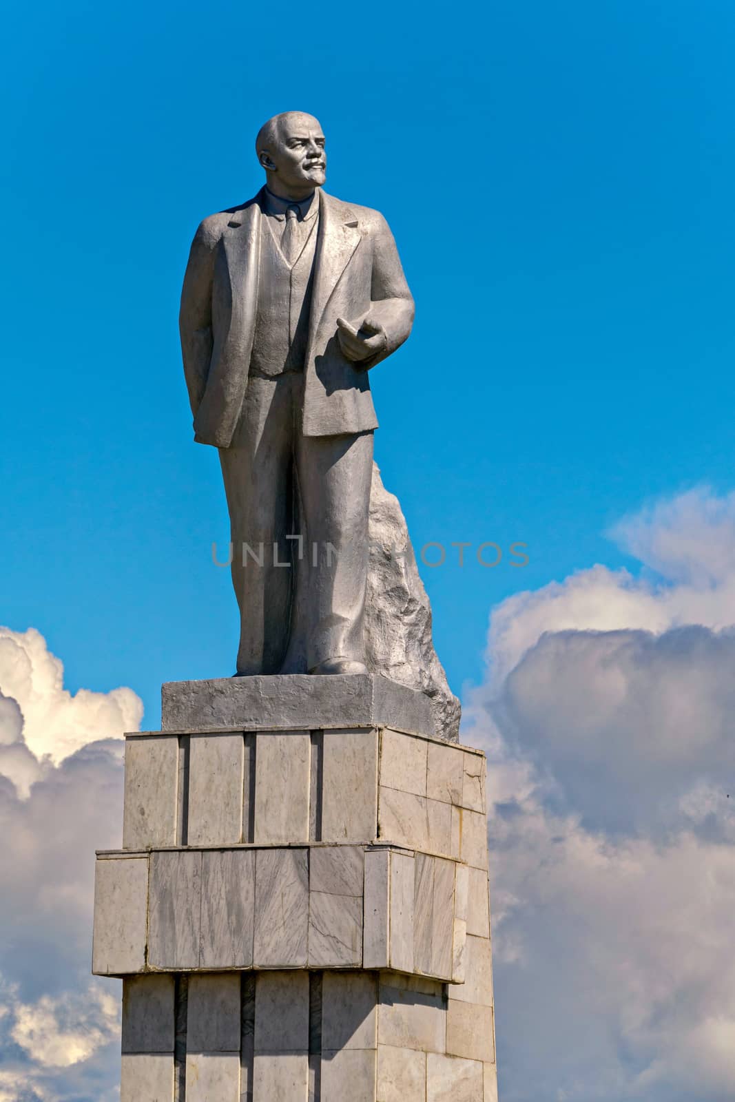 Monument to the totalitarian leader against the blue sky with white clouds by Adamchuk