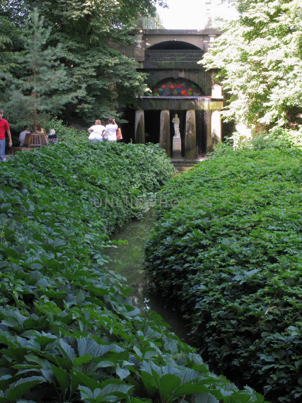 A small river ditch leading to the sculpture of a woman on the background of a building with huge columns