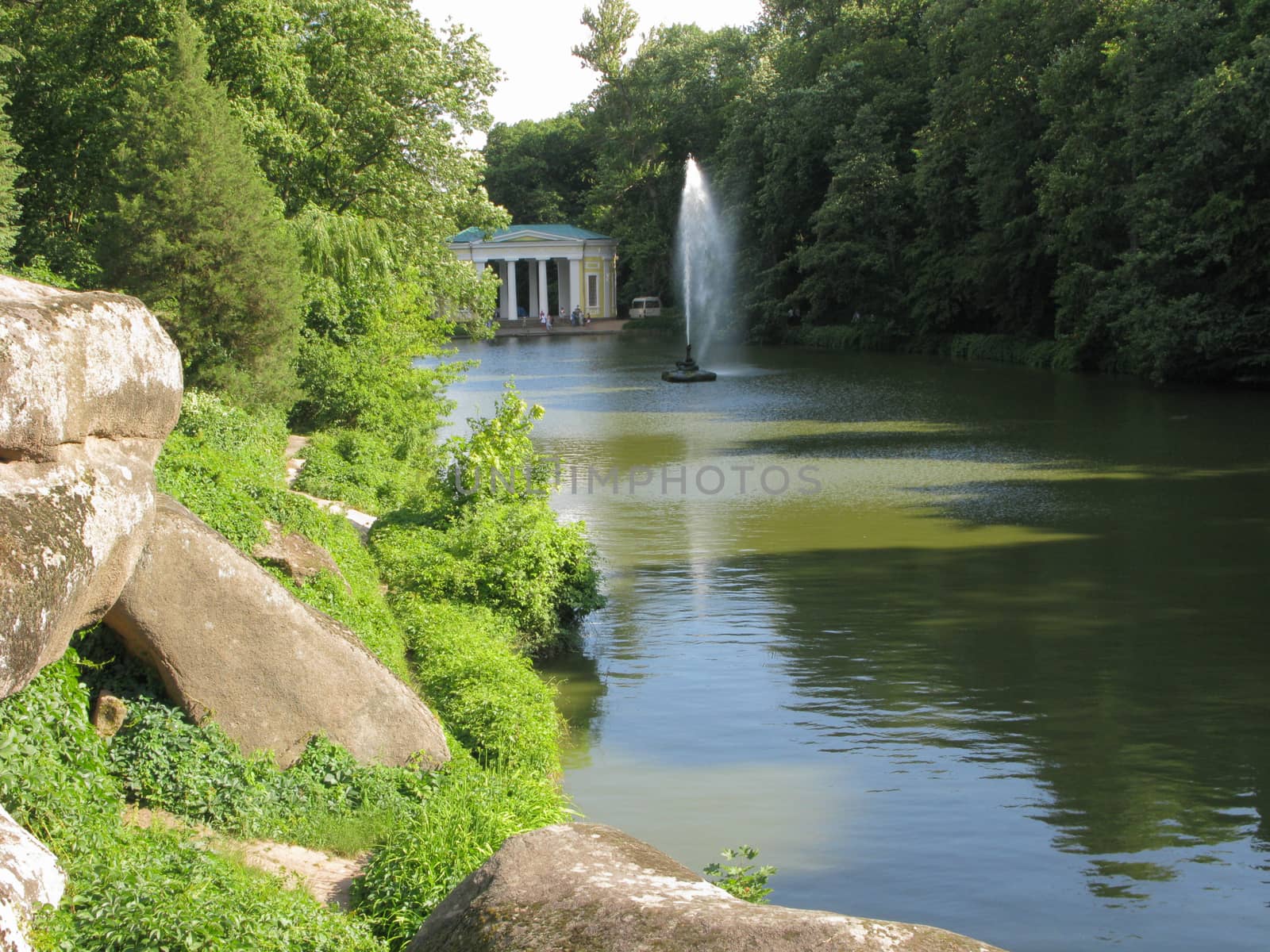 Rocky rocky shore of a transparent lake with a large hitting up fountain