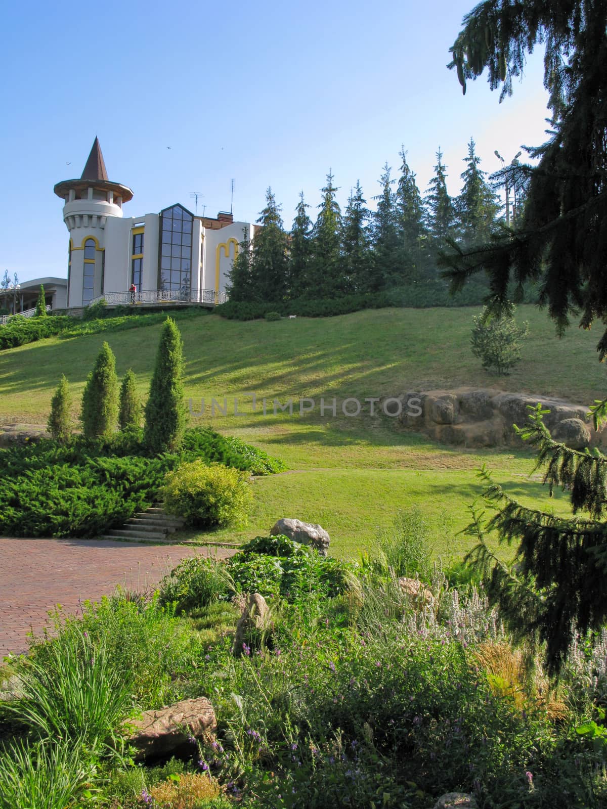 the path of the park against the background of a row of fir trees and a beautiful fairy-tale building by Adamchuk