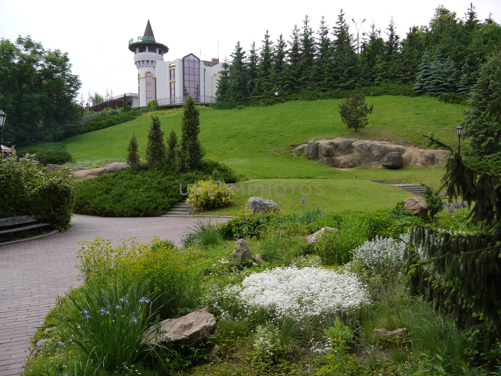 The palace with a beautiful green lawn around, with large stones, bushes, trees and a flower bed