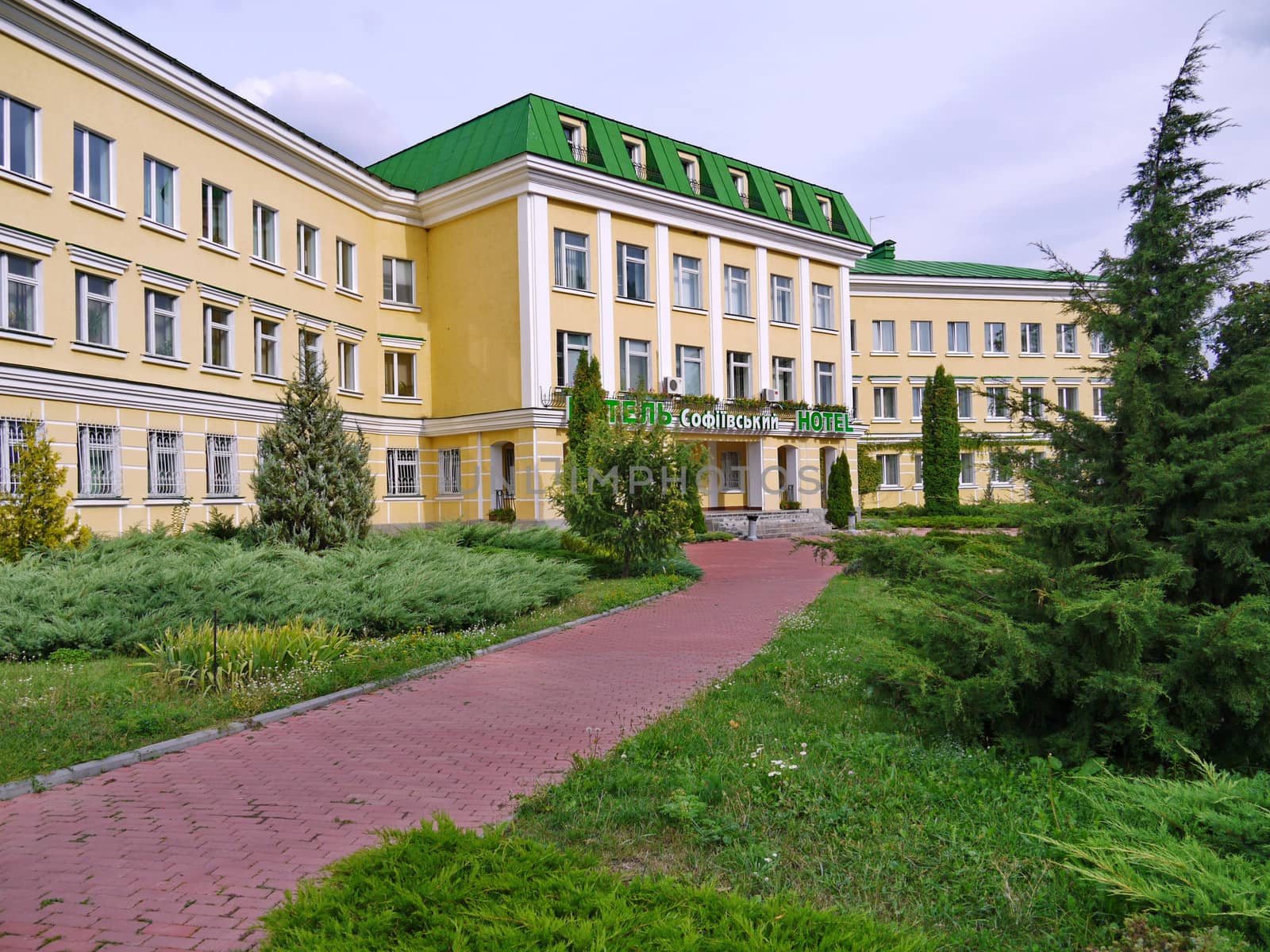 paths among green lawns leading to the entrance to a modern-looking hotel