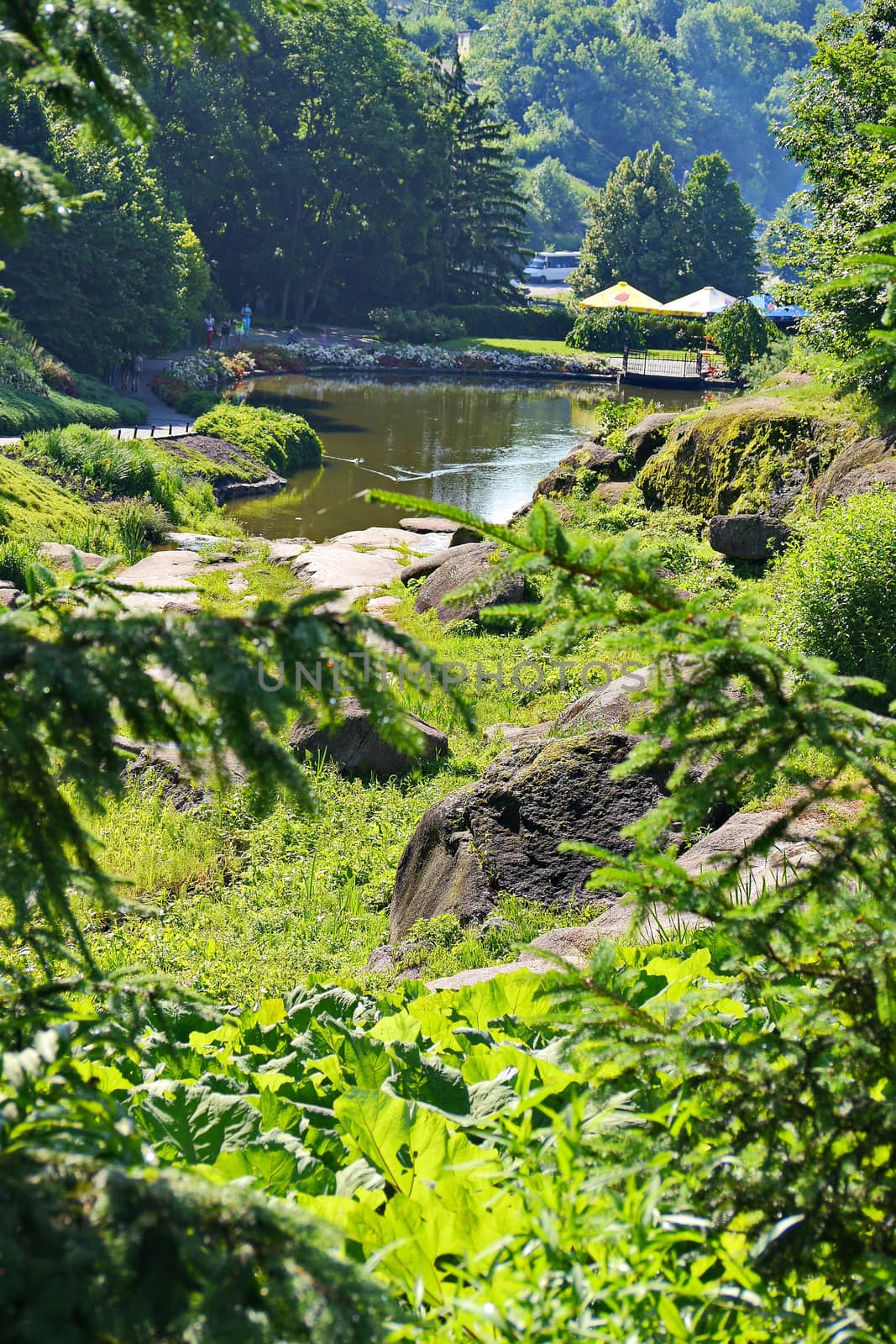 A small decorative transparent lake with stone boulders and beach umbrellas