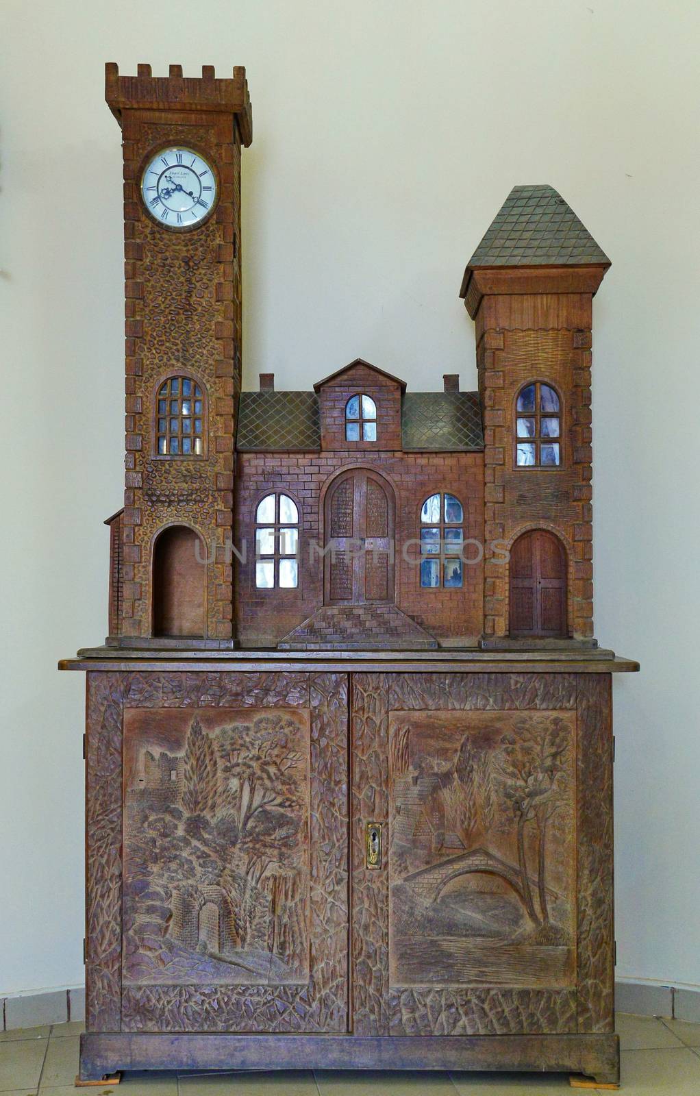 Carved wooden hand-made cabinet made of wood. With beautiful turrets with glasses and clocks. And the pictures on the doors are carved directly on them. by Adamchuk