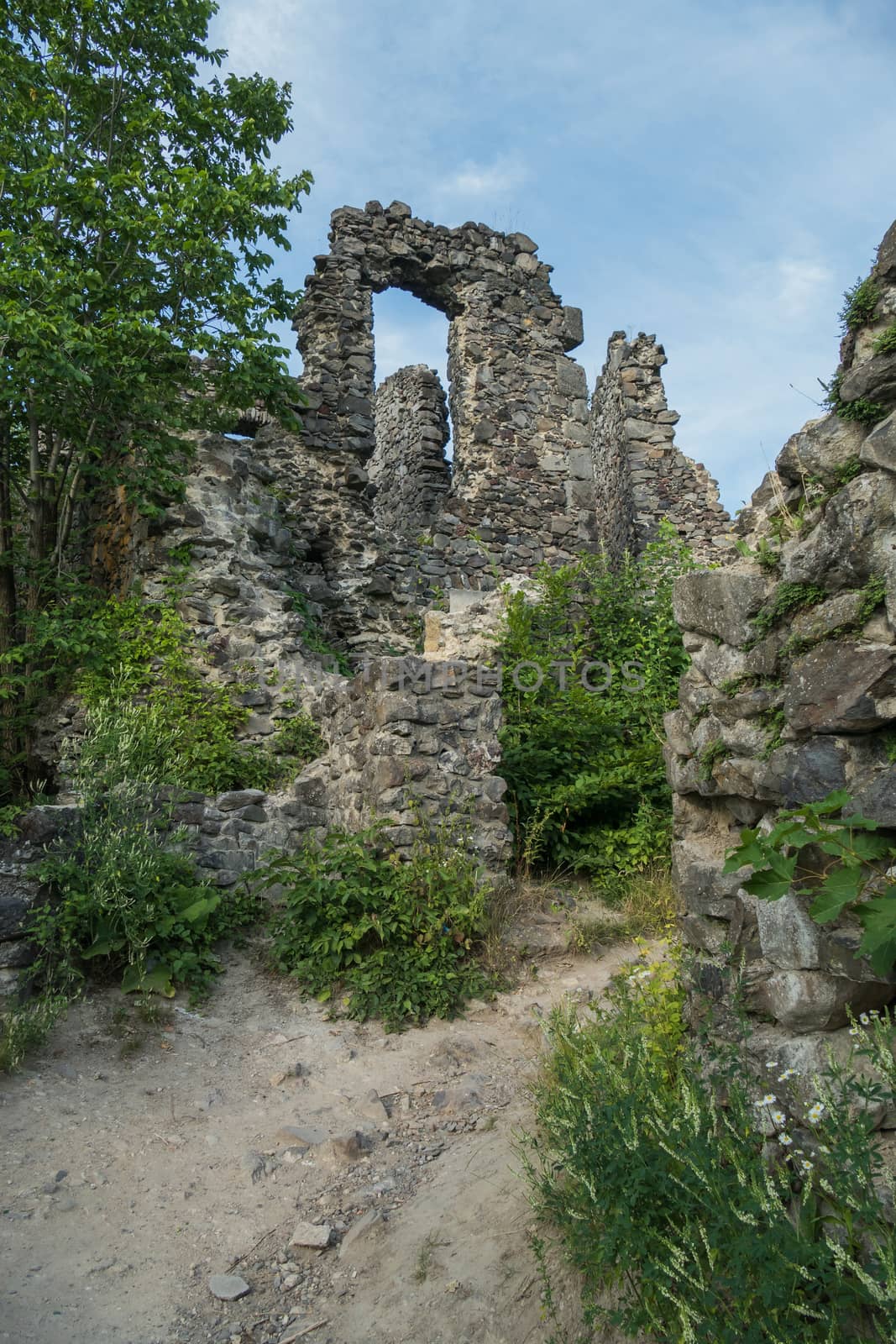 The ancient ruins of the old castle are overgrown with grass and shrubs with stones that have fallen out from time and weather from the walls.