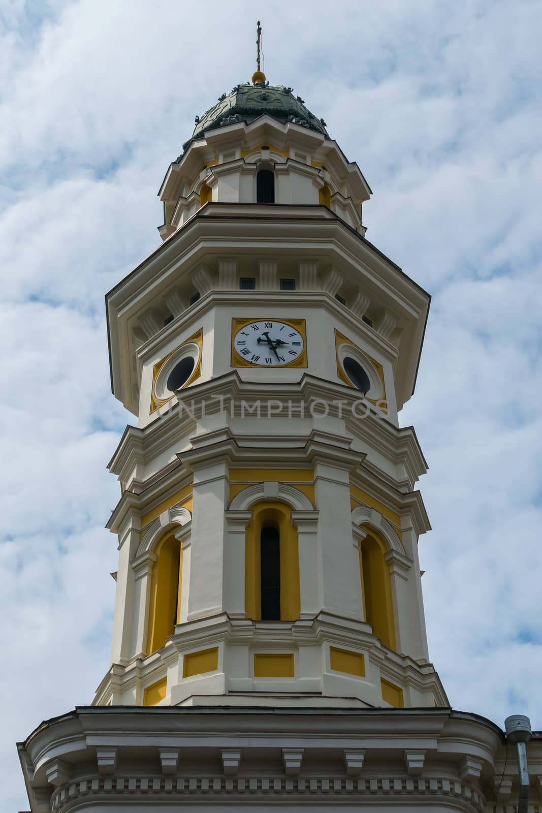 Ancient beautiful tower with a clock with a pointed spire on the top piercing the heavens by Adamchuk