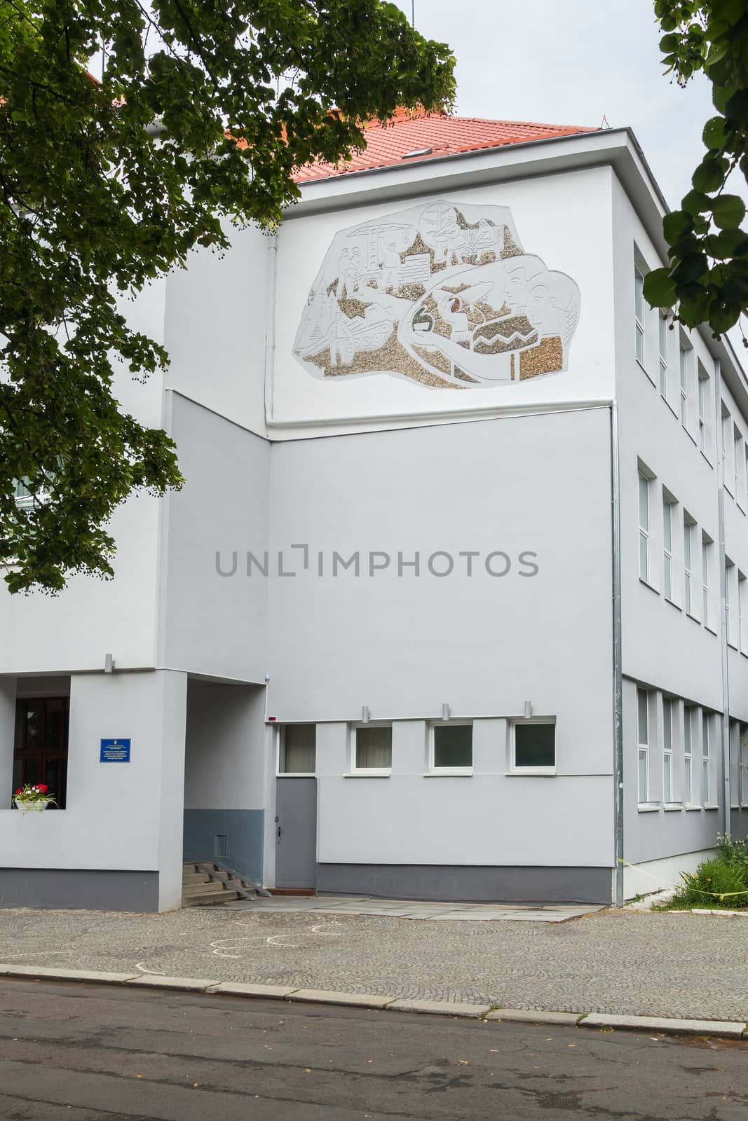 Entrance to a three-story building with white-gray walls and a red roof by Adamchuk