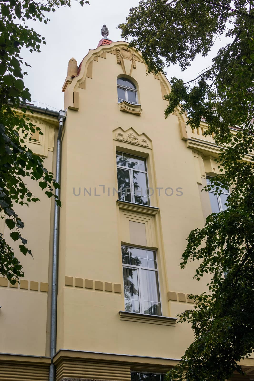 facade of a beautiful building against the background of green leaves by Adamchuk