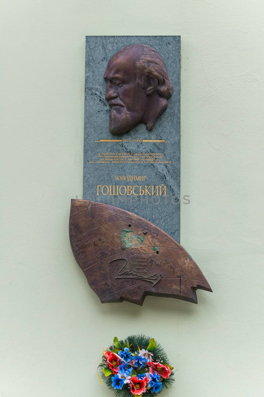A commemorative plaque set on the wall by an outstanding musician with written years of his life and beautifully decorated with flowers underneath her. by Adamchuk