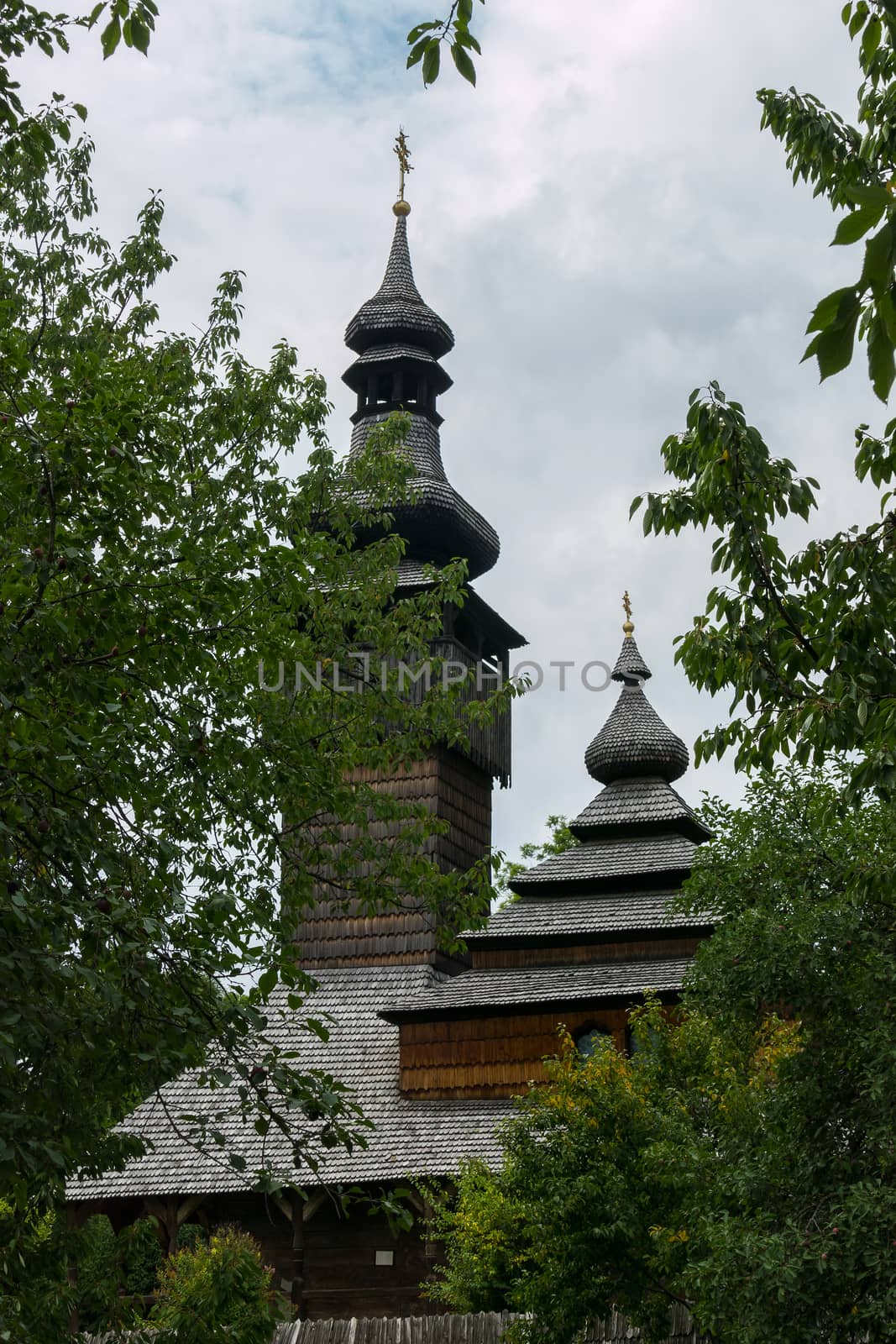 An old church with wooden domes in Transcarpathia in a green park by Adamchuk