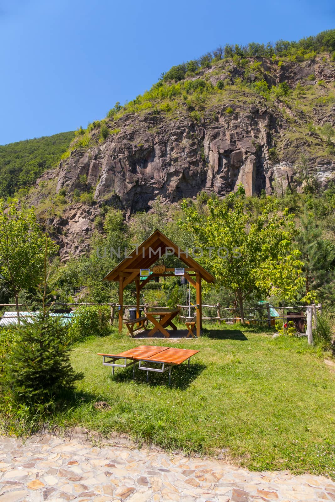 Green recreation area with gazebo and sun beds against the backdrop of a rocky mountain