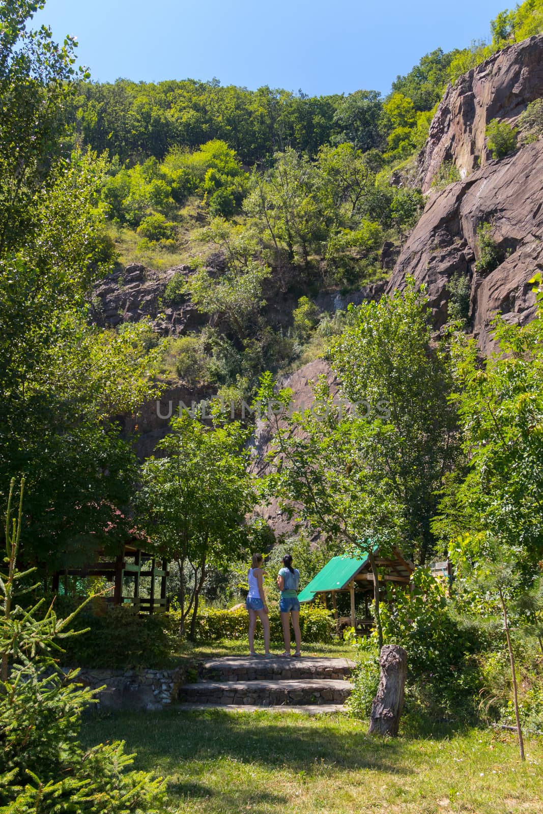 Girls climbing the stairs to the gazebos with green roofs against the backdrop of a large rocky mountain
