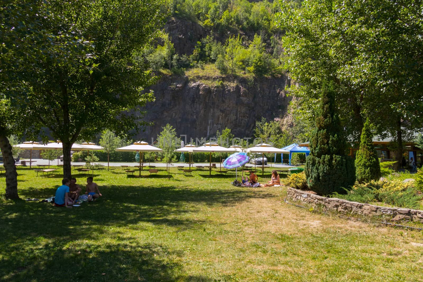 A place for tourists to relax in the form of tents and sun beds with umbrellas against the backdrop of a rocky mountain