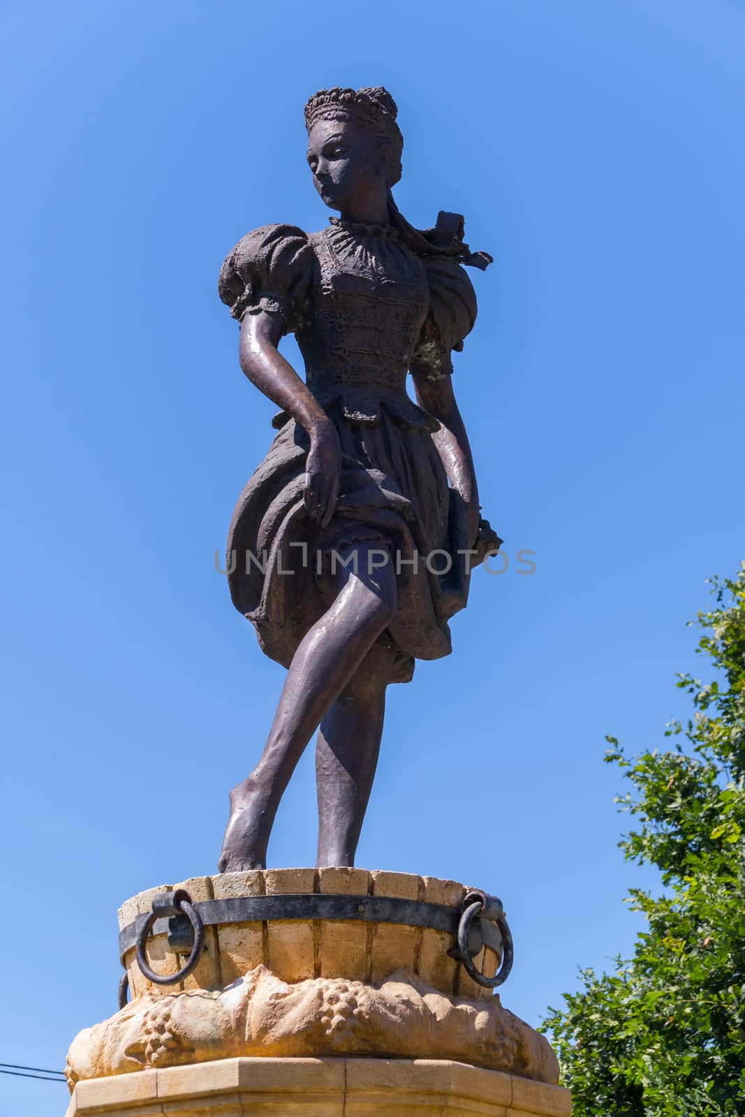 Bronze statue of a girl pressing grapes in a wooden bucket by Adamchuk