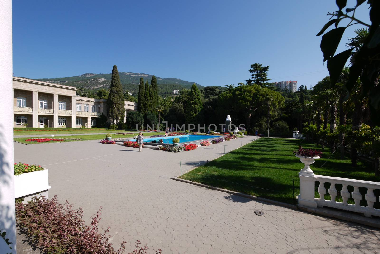 Beautiful view of the pool in the park with lovely flowers around and tourists taking pictures against the background of all this splendor.