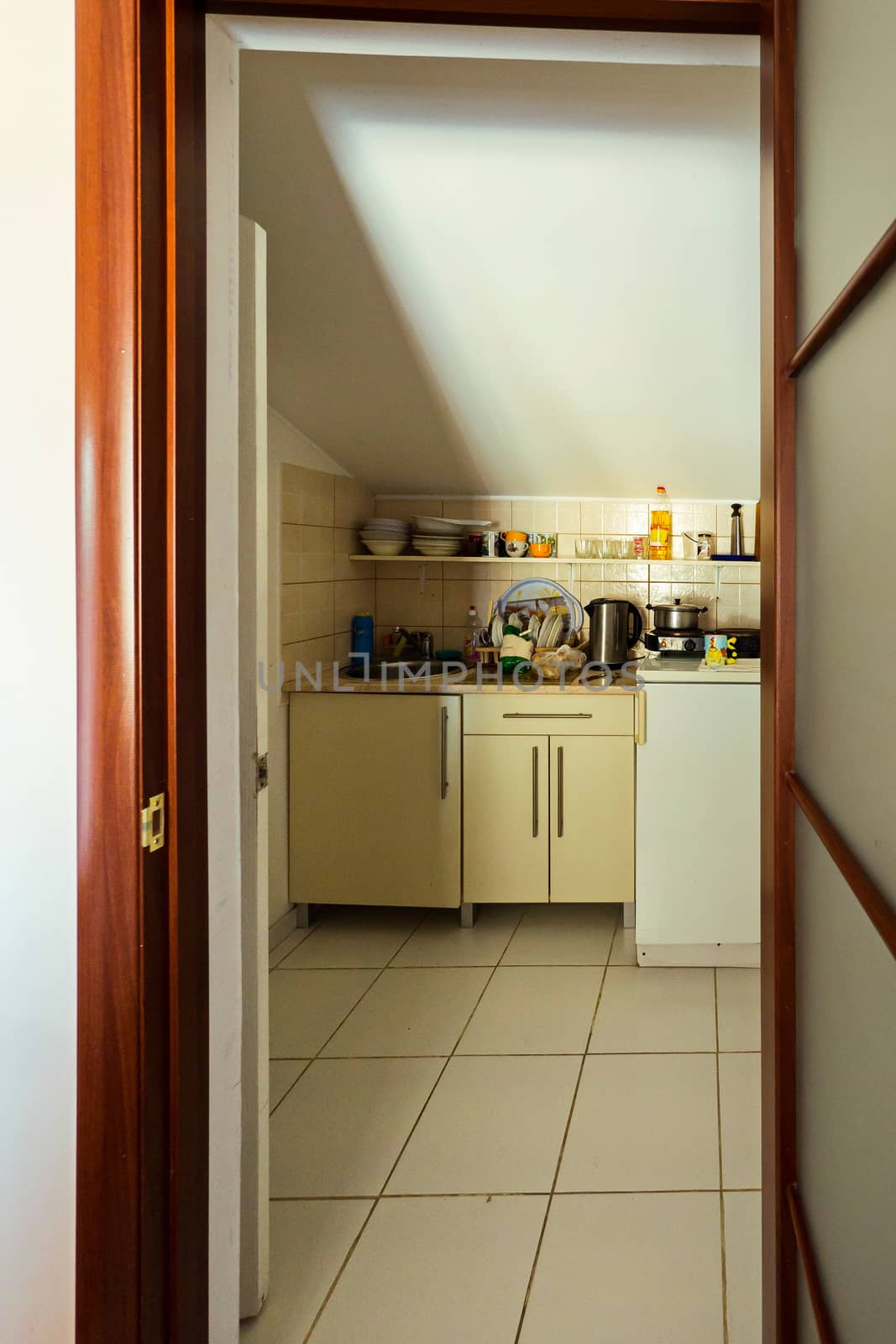 entrance through the wooden door to the room with bedside tables and cooking utensils by Adamchuk