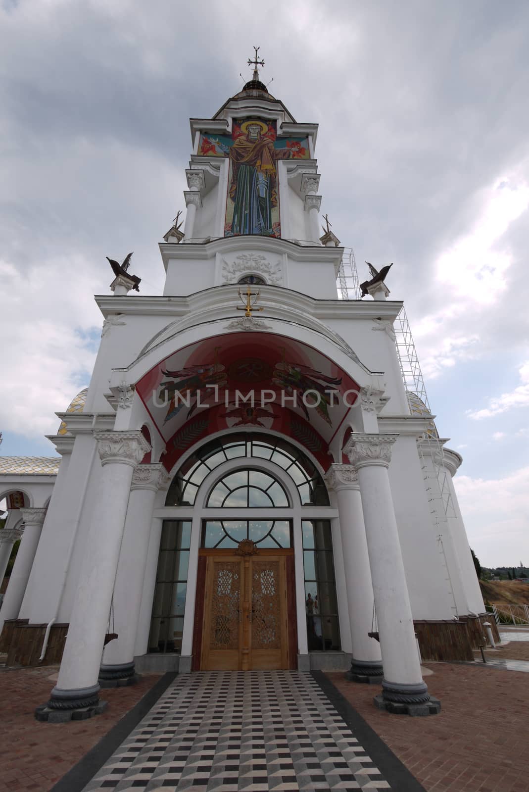 Beautiful central entrance to the church church with white columns and religious paintings by Adamchuk