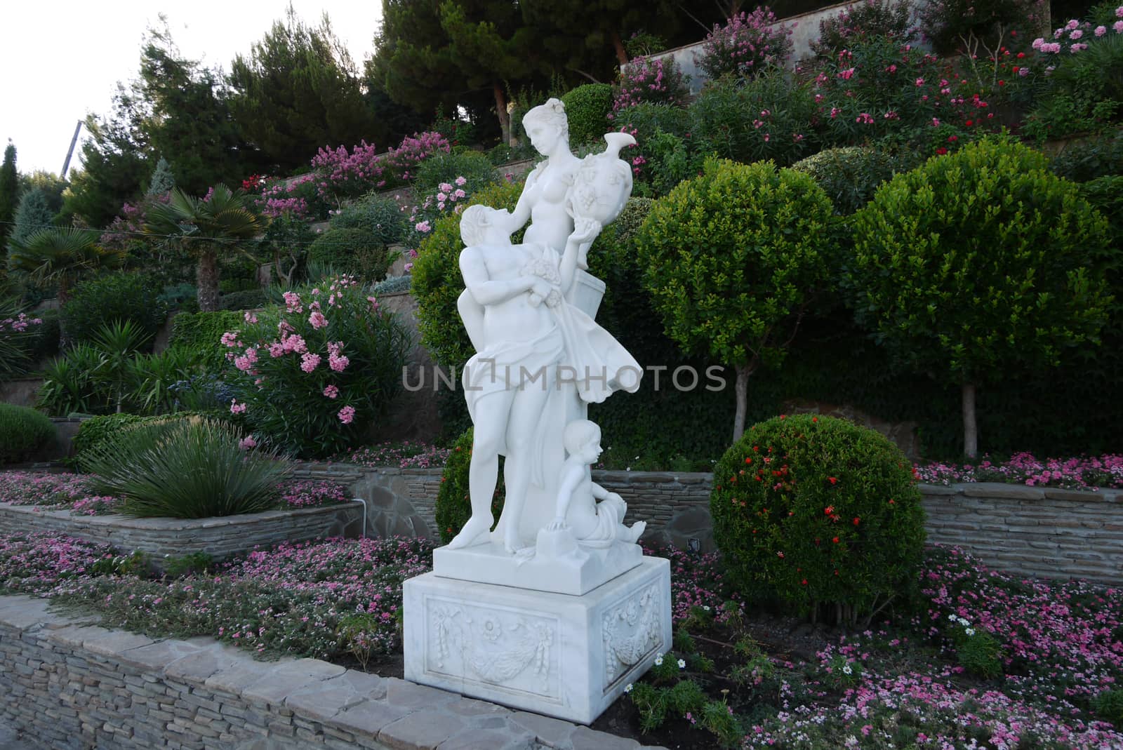 white garden sculpture on the background of beautiful plants by Adamchuk