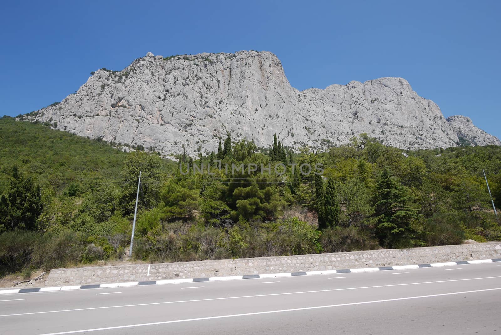A wide track with several dividing strips against the background of a rocky mountain