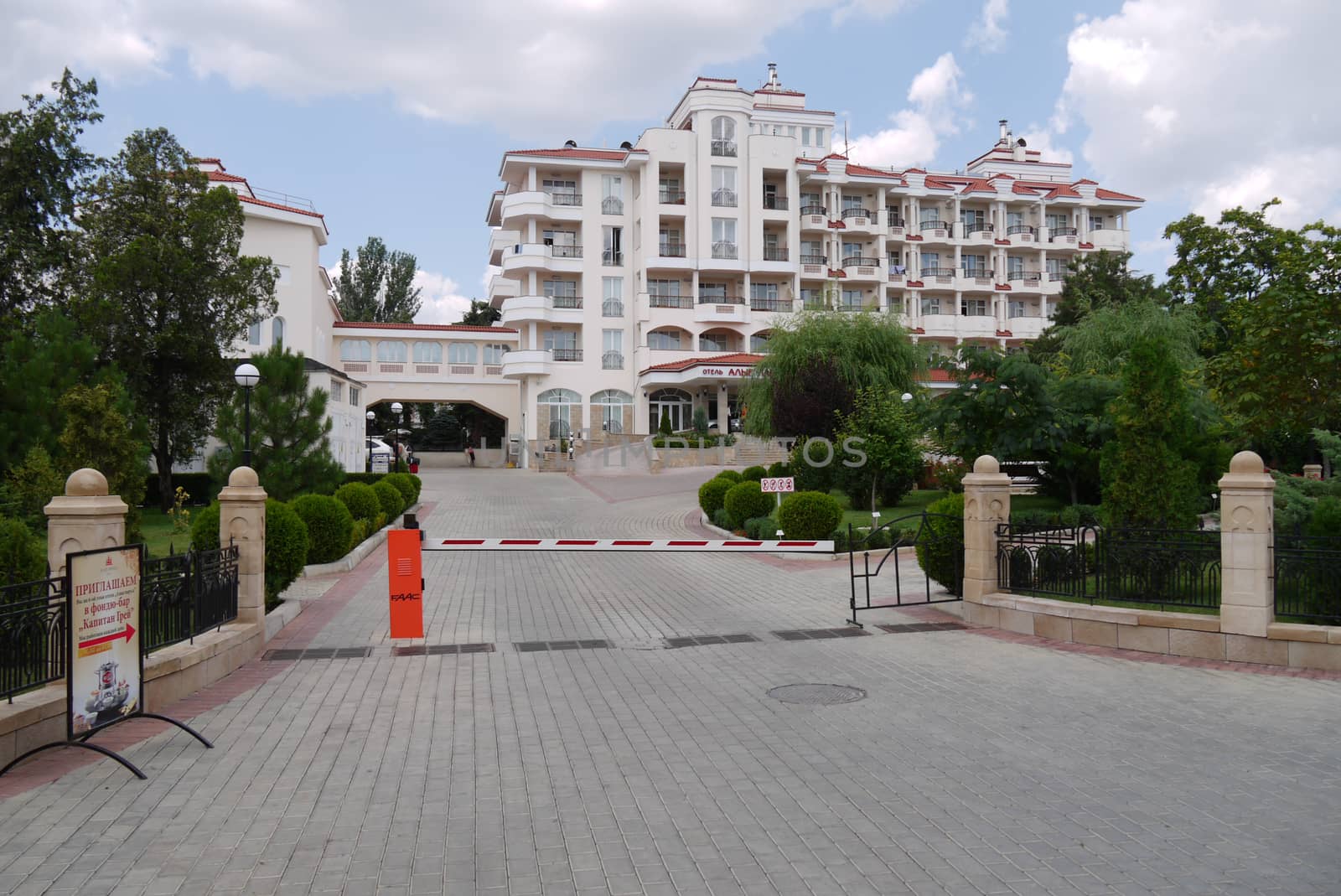 A paved road leads to a representative hotel with a barrier blocking the gates