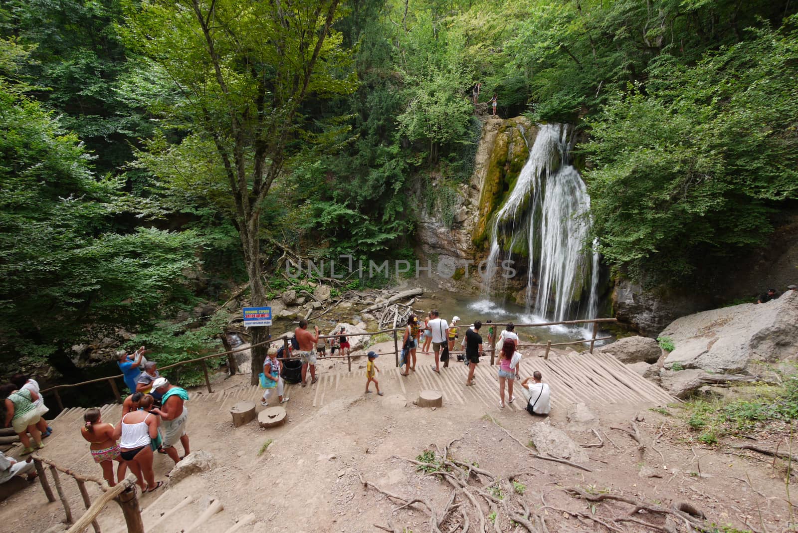 A group of tourists near a small waterfall. And around it is fresh, moist air