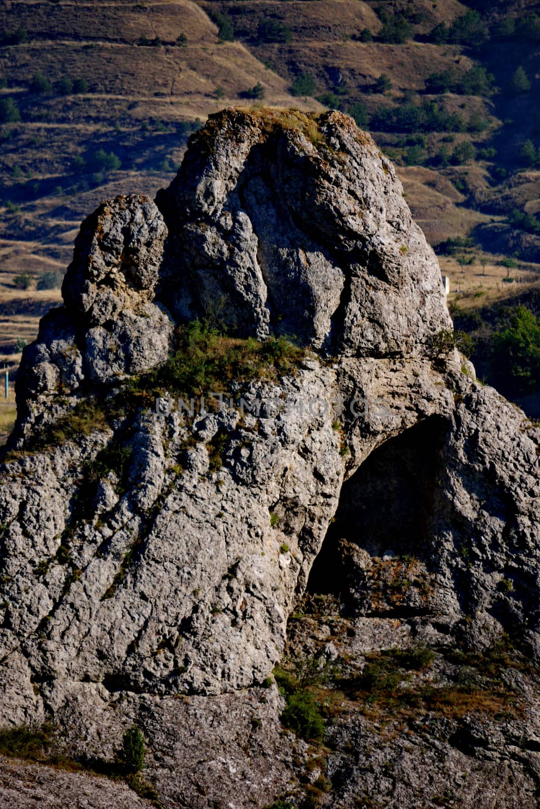 A rock with a small arch on a rocky mountain. Beautiful landscape