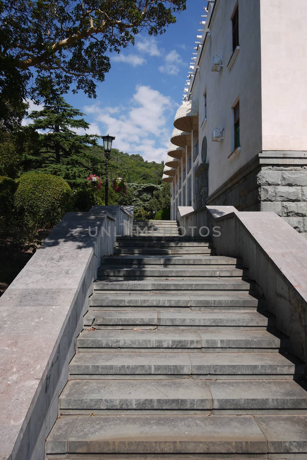 A ladder with granite steps going up along the building and mountain slopes in the distance by Adamchuk
