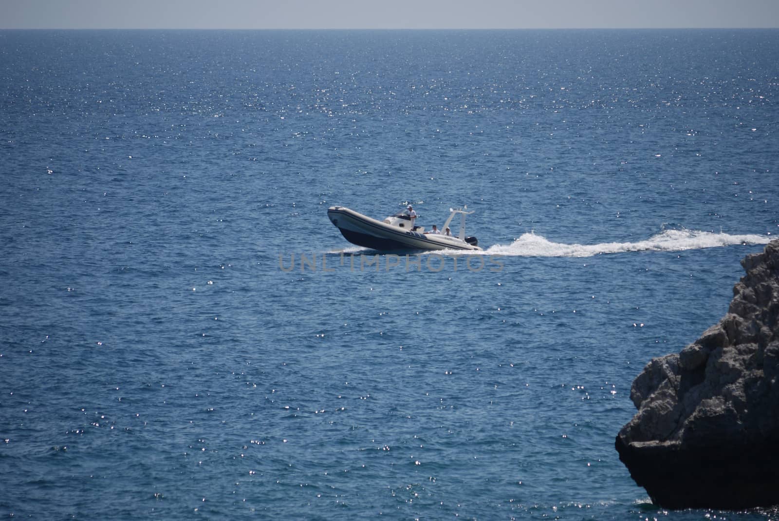 The boat is fast floating on the waves in the rays of sunlight against the background of the wide blue sea